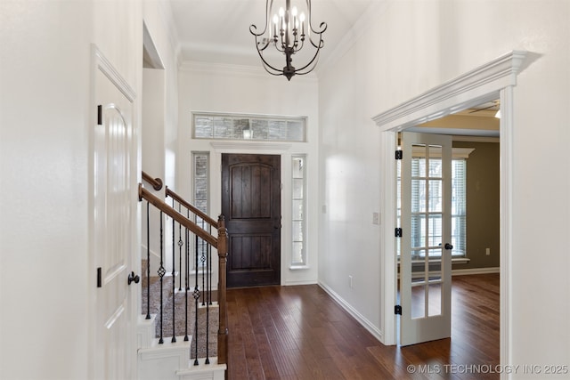 entryway with a notable chandelier, crown molding, and dark wood-type flooring