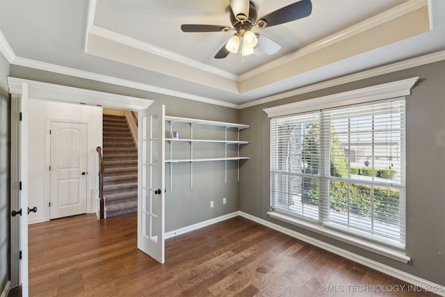 spare room with ceiling fan, dark hardwood / wood-style flooring, crown molding, and a tray ceiling