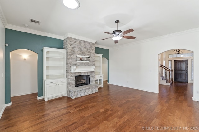 unfurnished living room with dark hardwood / wood-style flooring, a stone fireplace, ceiling fan, and crown molding