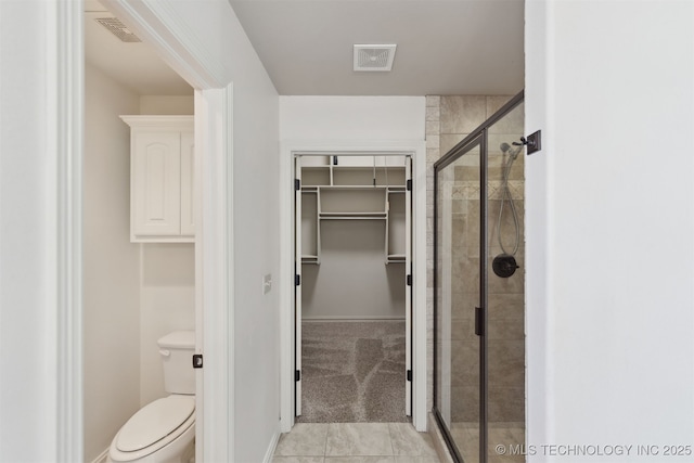 bathroom with a shower with shower door and toilet