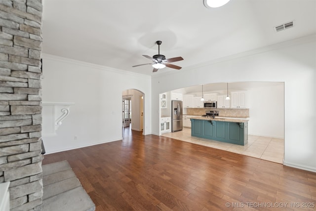 unfurnished living room featuring ceiling fan, light hardwood / wood-style flooring, and ornamental molding