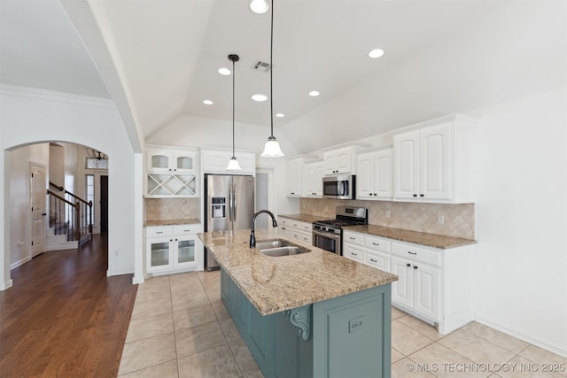 kitchen with sink, stainless steel appliances, an island with sink, pendant lighting, and white cabinets