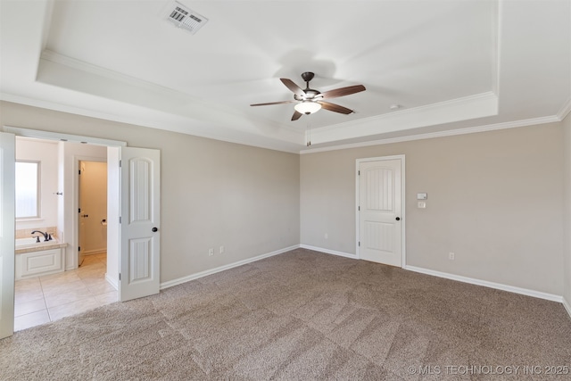 carpeted spare room with ceiling fan, crown molding, and a tray ceiling