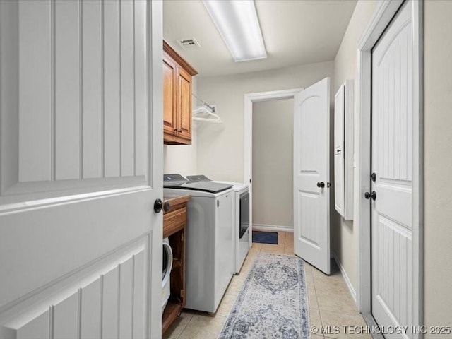 washroom with cabinets, light tile patterned floors, and washer and clothes dryer