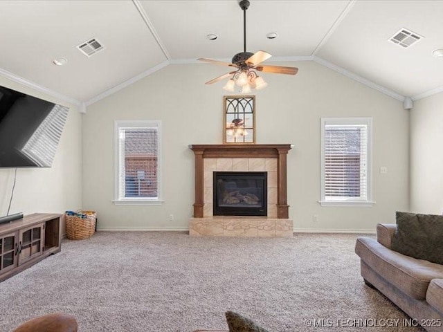 carpeted living room featuring a tiled fireplace, ceiling fan, crown molding, and vaulted ceiling