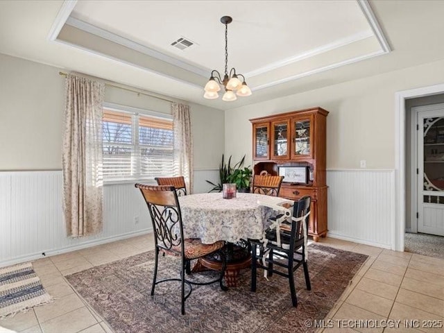 tiled dining area featuring a notable chandelier, ornamental molding, and a tray ceiling