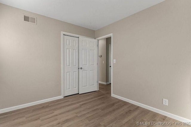 unfurnished bedroom with light wood-type flooring and a closet