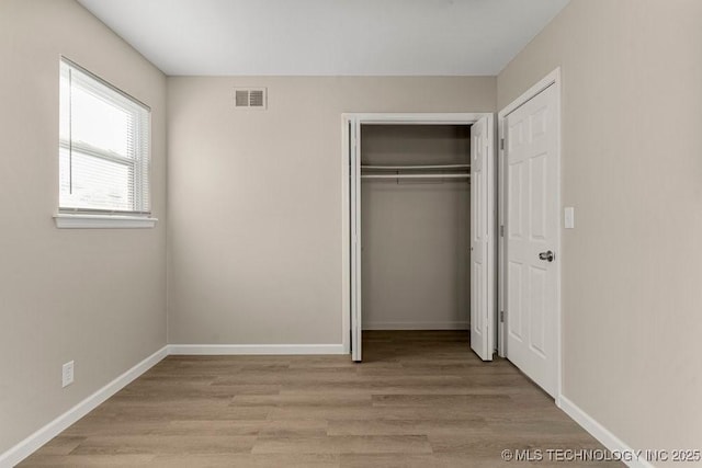 unfurnished bedroom with light hardwood / wood-style floors and a closet