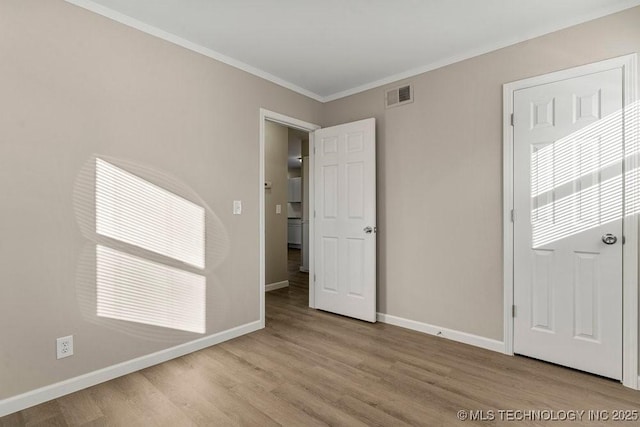 unfurnished room featuring light hardwood / wood-style flooring and crown molding