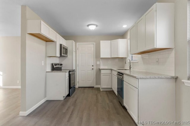 kitchen with tasteful backsplash, sink, white cabinets, and appliances with stainless steel finishes