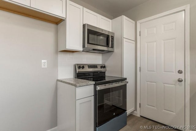 kitchen featuring light stone countertops, appliances with stainless steel finishes, backsplash, dark hardwood / wood-style floors, and white cabinetry