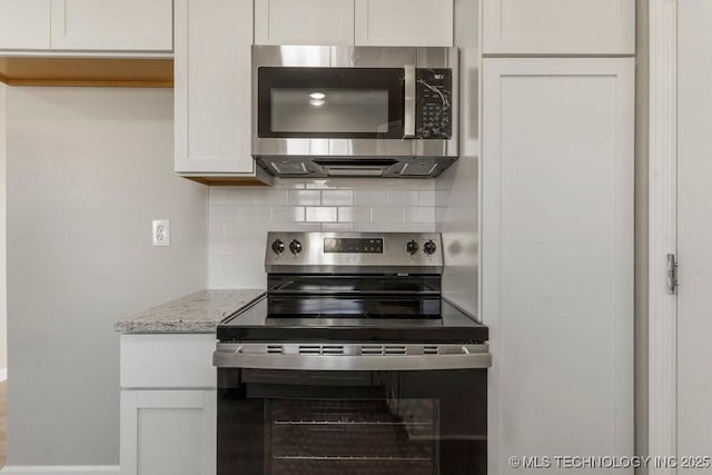 kitchen featuring decorative backsplash, light stone counters, white cabinetry, and appliances with stainless steel finishes