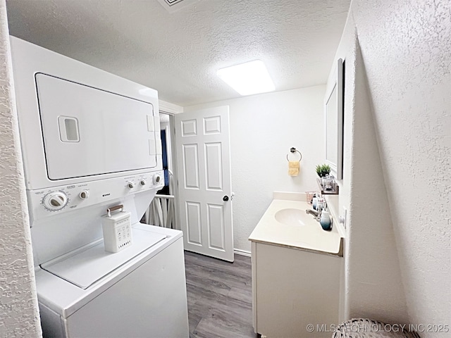 laundry room featuring a textured ceiling, sink, dark hardwood / wood-style flooring, and stacked washer / dryer