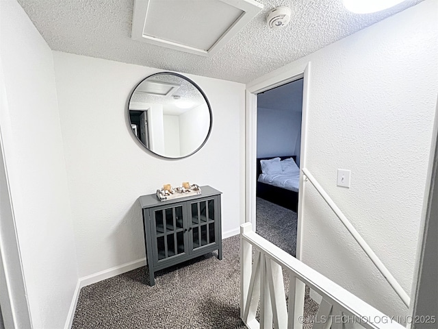 hall featuring a textured ceiling and carpet floors