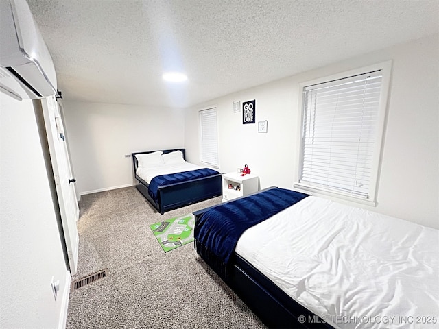 bedroom featuring an AC wall unit, carpet floors, and a textured ceiling