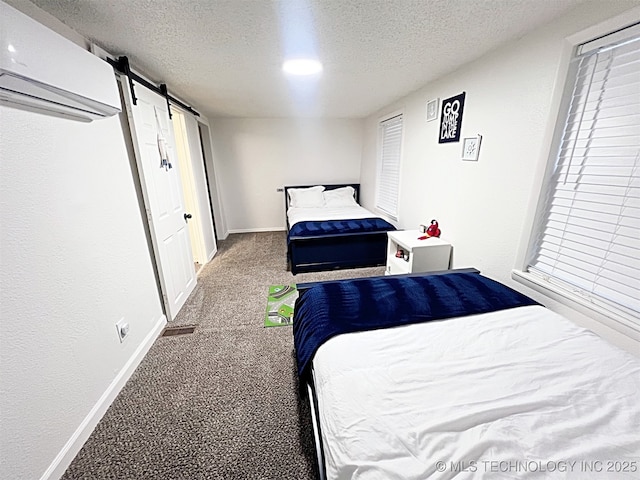 carpeted bedroom with an AC wall unit, a barn door, and a textured ceiling