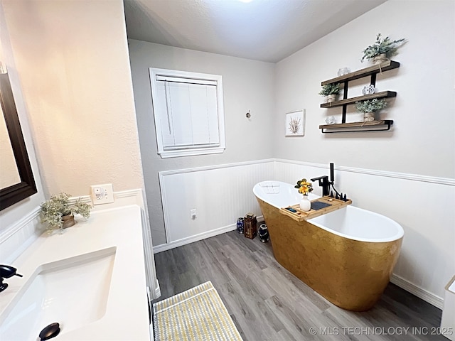 bathroom featuring hardwood / wood-style flooring, vanity, and a tub to relax in