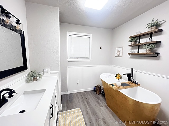 bathroom with hardwood / wood-style flooring, a washtub, a textured ceiling, and vanity