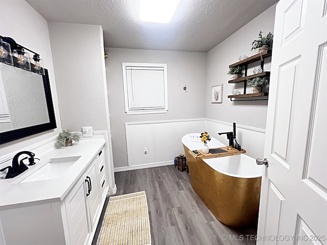 bathroom featuring hardwood / wood-style flooring, a washtub, a textured ceiling, and vanity