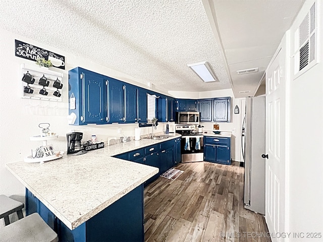 kitchen featuring blue cabinetry, sink, kitchen peninsula, a breakfast bar area, and appliances with stainless steel finishes