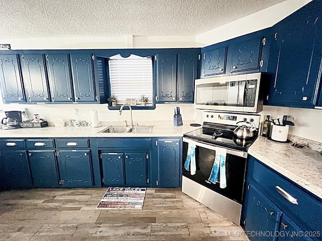 kitchen featuring blue cabinetry, a textured ceiling, stainless steel appliances, and sink