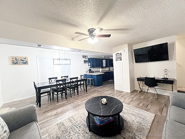 living room featuring a textured ceiling, light hardwood / wood-style flooring, and ceiling fan