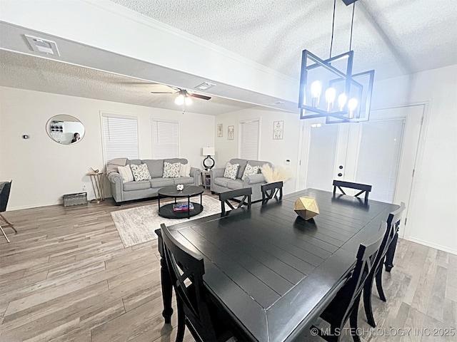 dining room featuring ceiling fan with notable chandelier, a textured ceiling, and hardwood / wood-style flooring