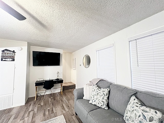 living room with a textured ceiling, hardwood / wood-style flooring, and ceiling fan