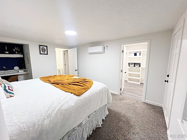 bedroom with carpet, a textured ceiling, and a wall mounted AC