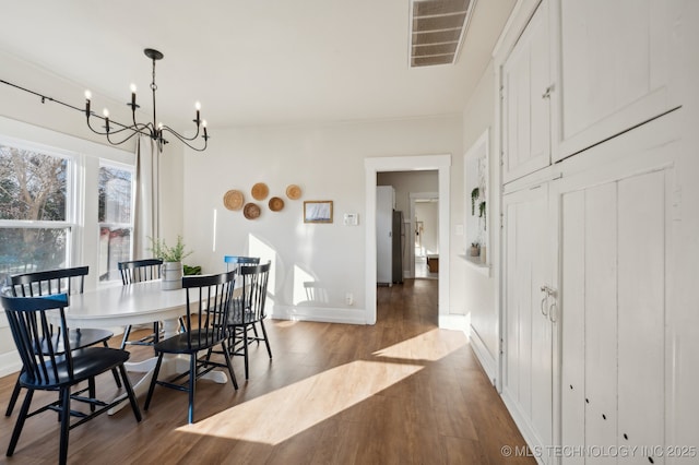 dining room with dark wood-type flooring and a notable chandelier