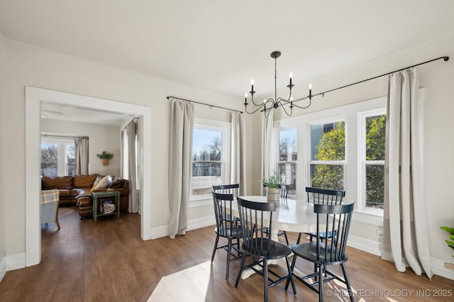 dining space with hardwood / wood-style floors, plenty of natural light, and an inviting chandelier