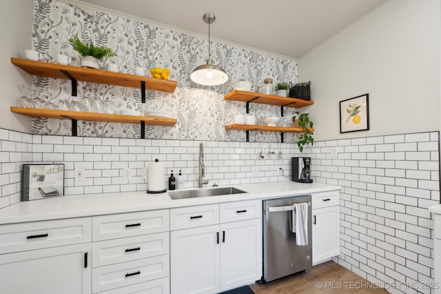 kitchen featuring white cabinets, crown molding, sink, hanging light fixtures, and stainless steel dishwasher