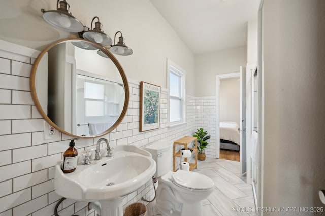 bathroom with tile patterned flooring, toilet, sink, and tile walls