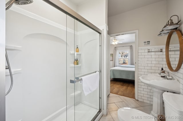 bathroom featuring tile patterned floors, ceiling fan, toilet, tile walls, and an enclosed shower