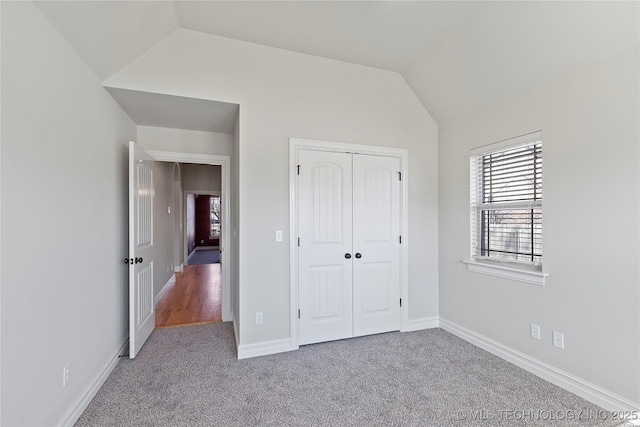 unfurnished bedroom with lofted ceiling, a closet, and carpet