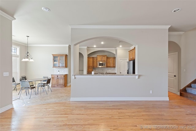 kitchen with decorative light fixtures, an inviting chandelier, backsplash, crown molding, and appliances with stainless steel finishes