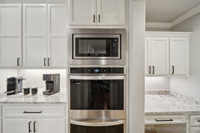 kitchen featuring stainless steel appliances, white cabinetry, ornamental molding, and light stone counters