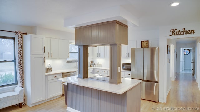 kitchen with stainless steel refrigerator, white cabinetry, backsplash, a kitchen island, and light wood-type flooring