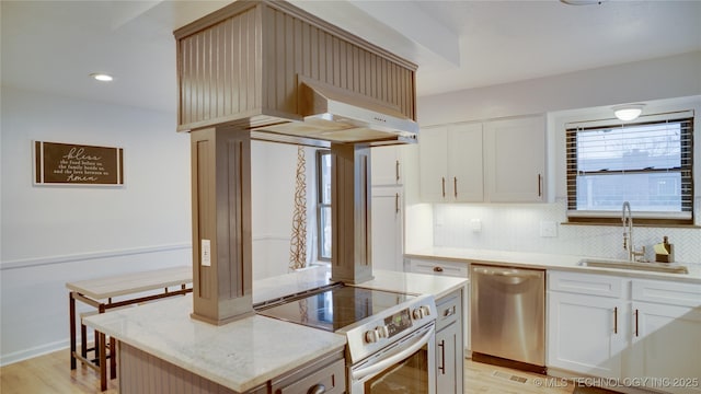 kitchen featuring appliances with stainless steel finishes, ventilation hood, sink, light hardwood / wood-style floors, and a kitchen island