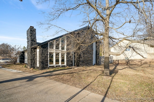 view of side of home featuring stone siding and a chimney