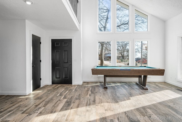 entryway featuring a textured ceiling, lofted ceiling, pool table, wood finished floors, and baseboards