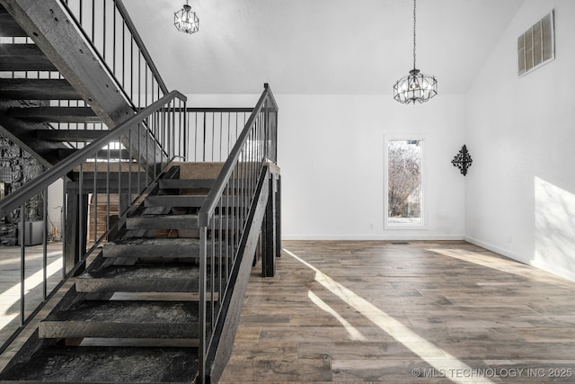 staircase with high vaulted ceiling, visible vents, a chandelier, and wood finished floors