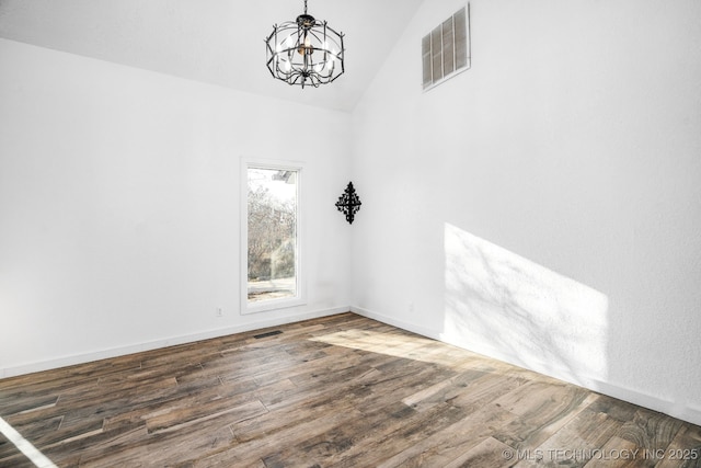 unfurnished dining area featuring baseboards, visible vents, lofted ceiling, wood finished floors, and a notable chandelier