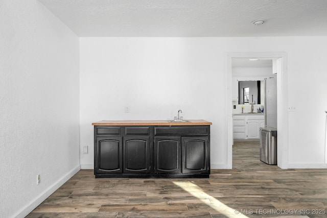 interior space with dark wood finished floors, a sink, a textured ceiling, and baseboards