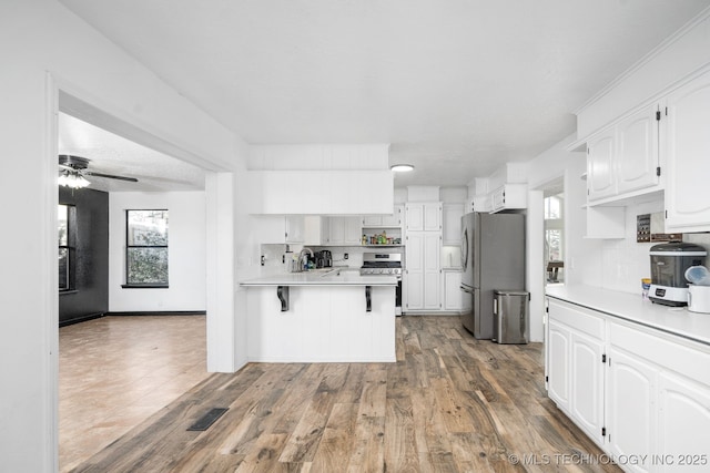 kitchen featuring stainless steel appliances, decorative backsplash, light countertops, and white cabinets