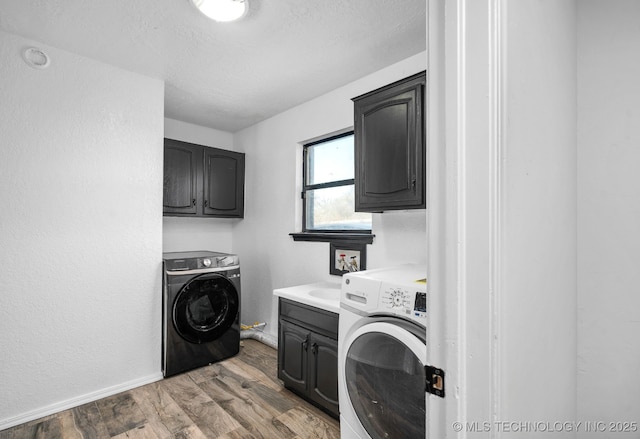 laundry room with cabinet space, a textured ceiling, baseboards, and wood finished floors