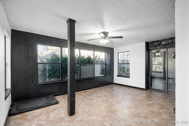 empty room with ceiling fan, baseboards, and a textured ceiling