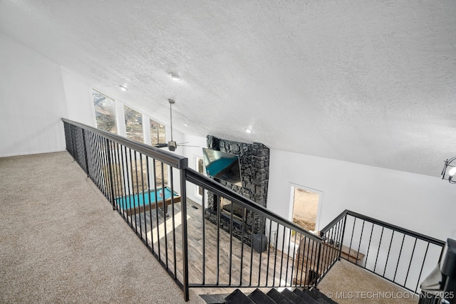 interior space with carpet, a textured ceiling, and an upstairs landing