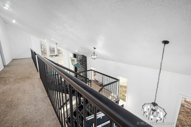 hall featuring a chandelier, carpet, lofted ceiling, and an upstairs landing