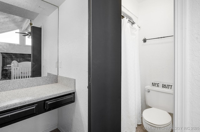 full bathroom with a textured wall, toilet, ceiling fan, curtained shower, and vanity